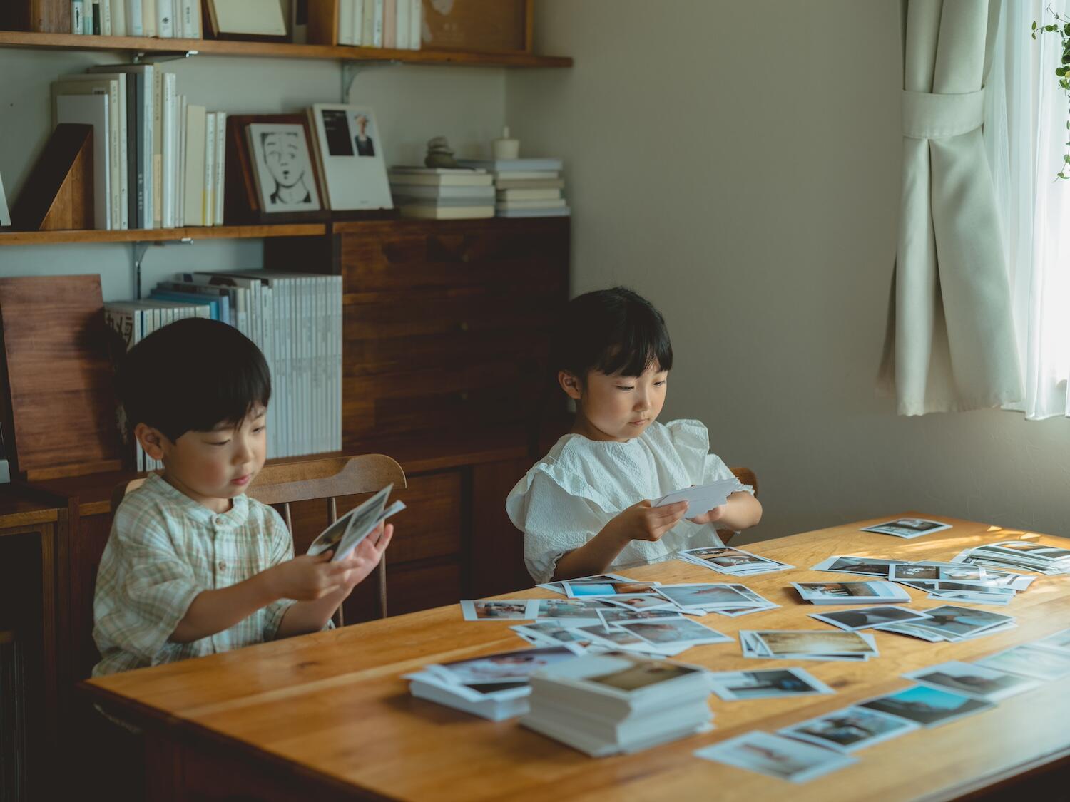 久慈さんの娘さんと息子さんがたくさんのプリント写真の中からお気に入りを真剣に選んでいる様子